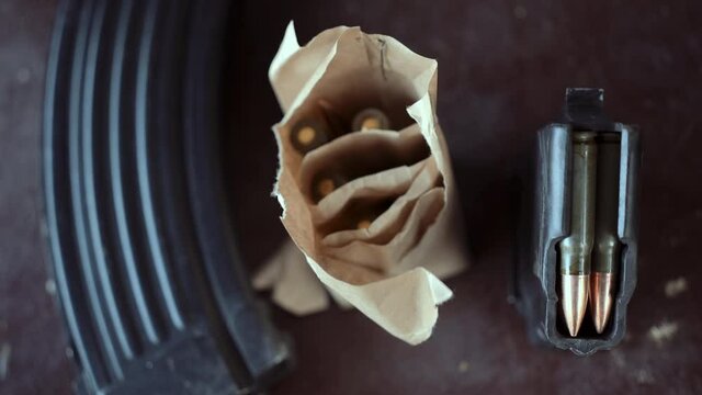 Bullets and magazine from the AK-47 Kalashnikov assault rifle. A man puts a magazine with bullets on the table.