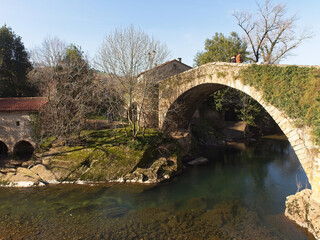 Fototapeta na wymiar The stone bridge over the river in Liérganes