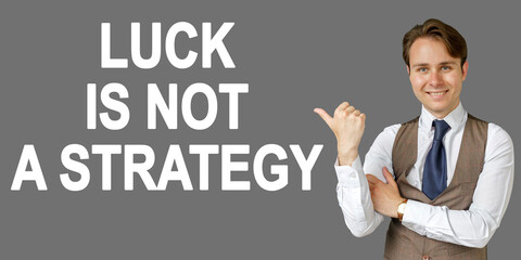 Emotional portrait of businessman showing right hand gesture on text - LUCK IS NOT A STRATEGY. Gray background.