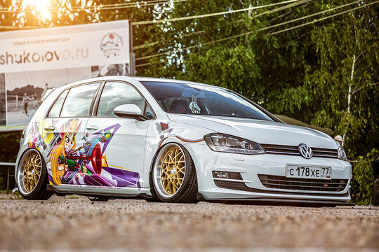 Moscow, Russia: July 06, 2019: Tuned by low suspension and custom wide golden colored wheels. White golf 7 with aerography on which painted Chip and Dale characters.