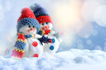 Two funny snowmen in winter on the snow.
