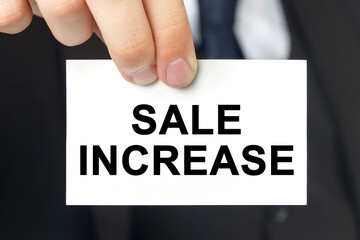 Businessman shows a card with the text SALE INCREASE