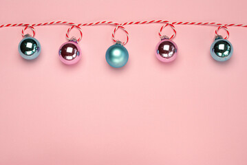 Fototapeta na wymiar Christmas composition, trendy colors. Banner of shiny christmass garland with pink and skyblue balls over pink background