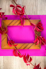 Empty photo frame and colorful autumn dry leaves on pink background. 