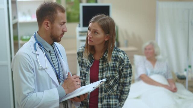 Caucasian doctor physician talking with young woman about her sick mother advising chemotherapy medication in the private clinic. Diagnosis. Medical issues. Appointment. Healthcare.