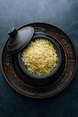 Basmati rice groats in a clay pot on a dark background