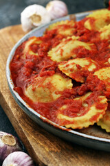 Ravioli with tomato sauce and basil on rustic background