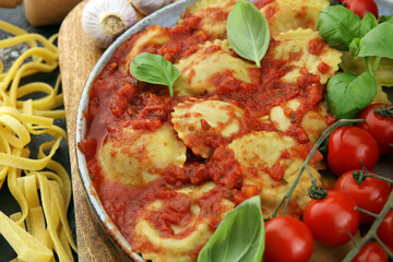 Ravioli with tomato sauce and basil on rustic background