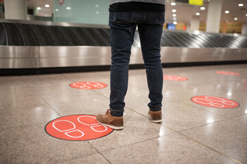 Man waiting for the arrival of his suitcases at the airport respecting the safety distance.