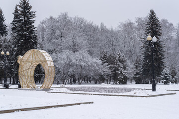 Winter in the park. Beautiful gold Christmas decoration in front of snow covered trees. 