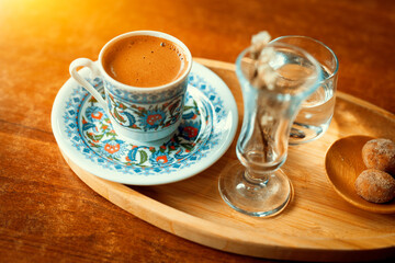 Traditional sparkling turkish coffee served with porcelain cup, cookies, glass of water and flower.