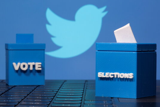 3D printed ballot boxes are seen in front of a displayed Twitter logo