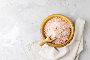 Pink Himalayan rock salt in a bowl and spoon on a light background. Top view, place for text.