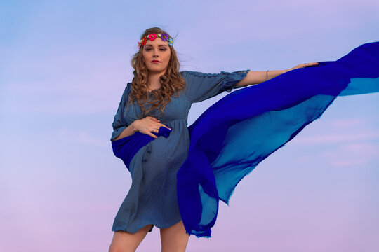 Pregnant woman against colorful sky with scarf flowing in wind