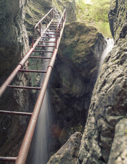 An old rusty iron staircase over a waterfall.Tamina Canyon, Romania