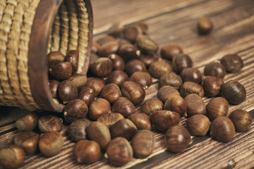 Fresh chestnuts in the basket falling on a brown wooden table