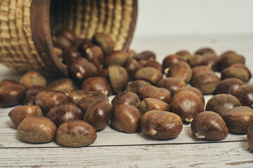 Fresh chestnuts in the basket falling on a white wooden table