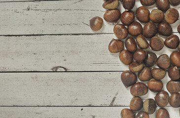 Top view of chestnuts on white wooden background with copy space for your text.