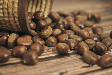 Fresh chestnuts in the basket falling on a brown wooden table