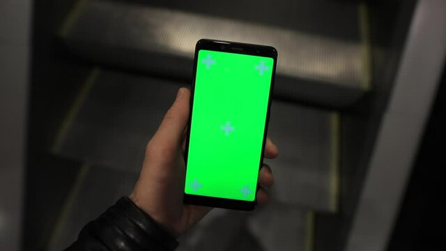 POV, male hand using smartphone with green screen chroma key in the escalator of shopping mall