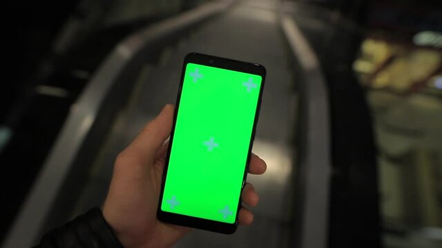 POV, male hand using smartphone with green screen chroma key in the escalator of shopping mall