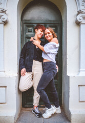 Girls couple standing posing in a dark green door on the street.