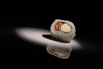 Closeup of a delicious sushi roll under the lights against a dark background
