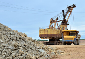 Obraz premium Mining truck and excavators working in the limestone open-pit. Loading and transportation of minerals in the dolomite mining quarry