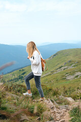 Naklejka premium Beautiful nature landscape in mountains. Girl enjoy scenics view on valley. Hiking journey on tourist trail. Outdoor adventure. Travel and exploration. Healthy lifestyle, leisure activities