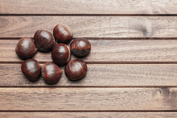 Obraz premium Chestnuts on wooden background, flat lay with copy space