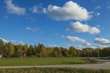 Fototapeta premium Gorgeous autumn colorful nature landscape view. Beautiful nature backgrounds. Green yellow trees and grass field on blue sky background.