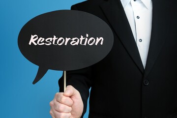 Restoration. Businessman holds speech bubble in his hand. Handwritten Word/Text on sign.