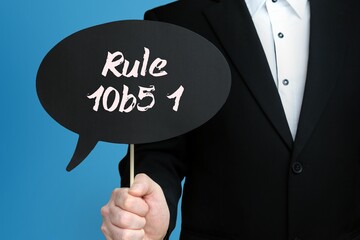 Rule 10b5 1. Businessman holds speech bubble in his hand. Handwritten Word/Text on sign.