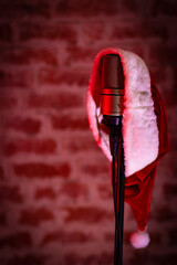 A Christmas concert photo with Santa Claus's hat hanging on a microphone, red spotlights and a...