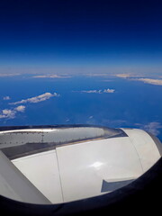 Fototapeta na wymiar view from airplane window with a turbine in the foreground and in the background an ocean covered by clouds under a cobalt blue sky