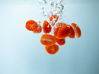 Fresh cherry tomatoes splashing into water