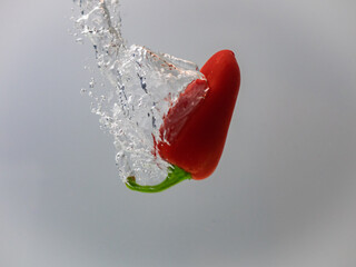Fresh pepper is splashing into water