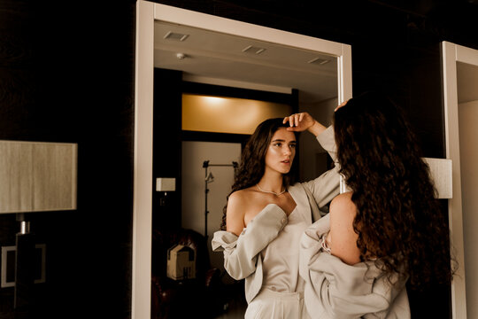 Sexy model and her reflection in the mirror. Attractive girl near the mirror. Young woman is looking at her reflection in the mirror. Perfect skin