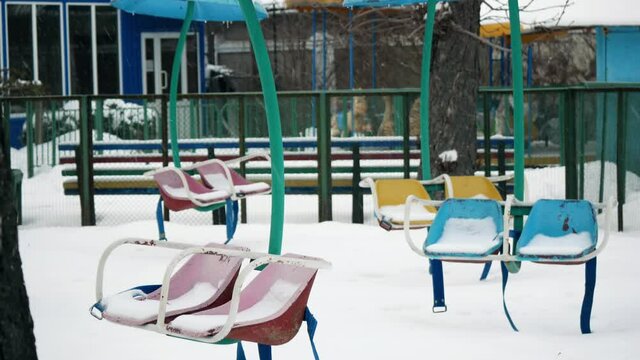 Old childrens carousel in an abandoned amusement park in winter with snow