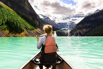 Young pretty woman canoeing on the Lake Louise, Canada. Concept about lifestyle, leisure, nature and travel. 