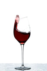 Close up view of splashing red wine in glass isolated on white background. 