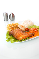 chicken rice salad and french fries in a white plate on a white table with salt and pepper