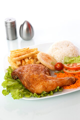 chicken rice salad and french fries in a white plate on a white table with salt and pepper