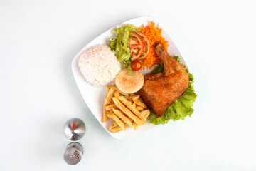 chicken rice salad and french fries in a white plate on a white table with salt and pepper