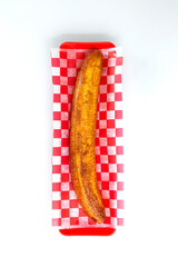 ripe banana on a plate with checkered napkin and red bowl on a white table