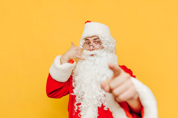 Cheerful santa claus showing phone gesture and finger to camera with smile on face. Santa shows a gesture call me. Christmas and New Year
