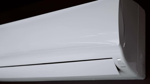 A man's hand directs the remote control to the air conditioner and presses the power button, the blinds are opened, the air conditioner drives cold air, then he turns it off. Close Up. Shallow depth o