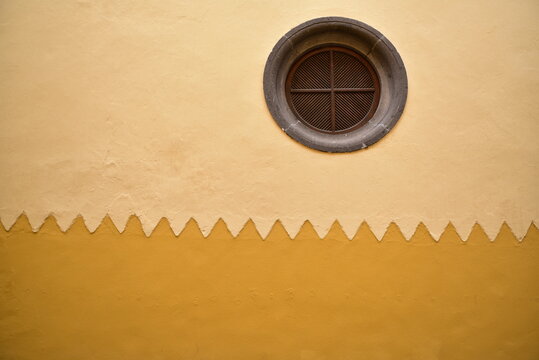 plaster wall in yellow tones with a round window