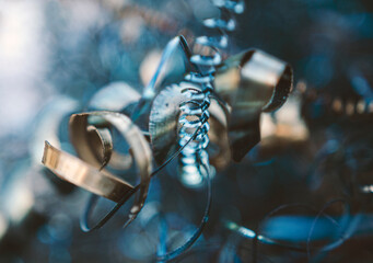 Colorful metal scraps of metal,  shaped like springs, shiny and catching light, blue and gold and...
