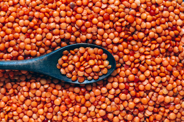 Wooden spoon in red lentils, food background